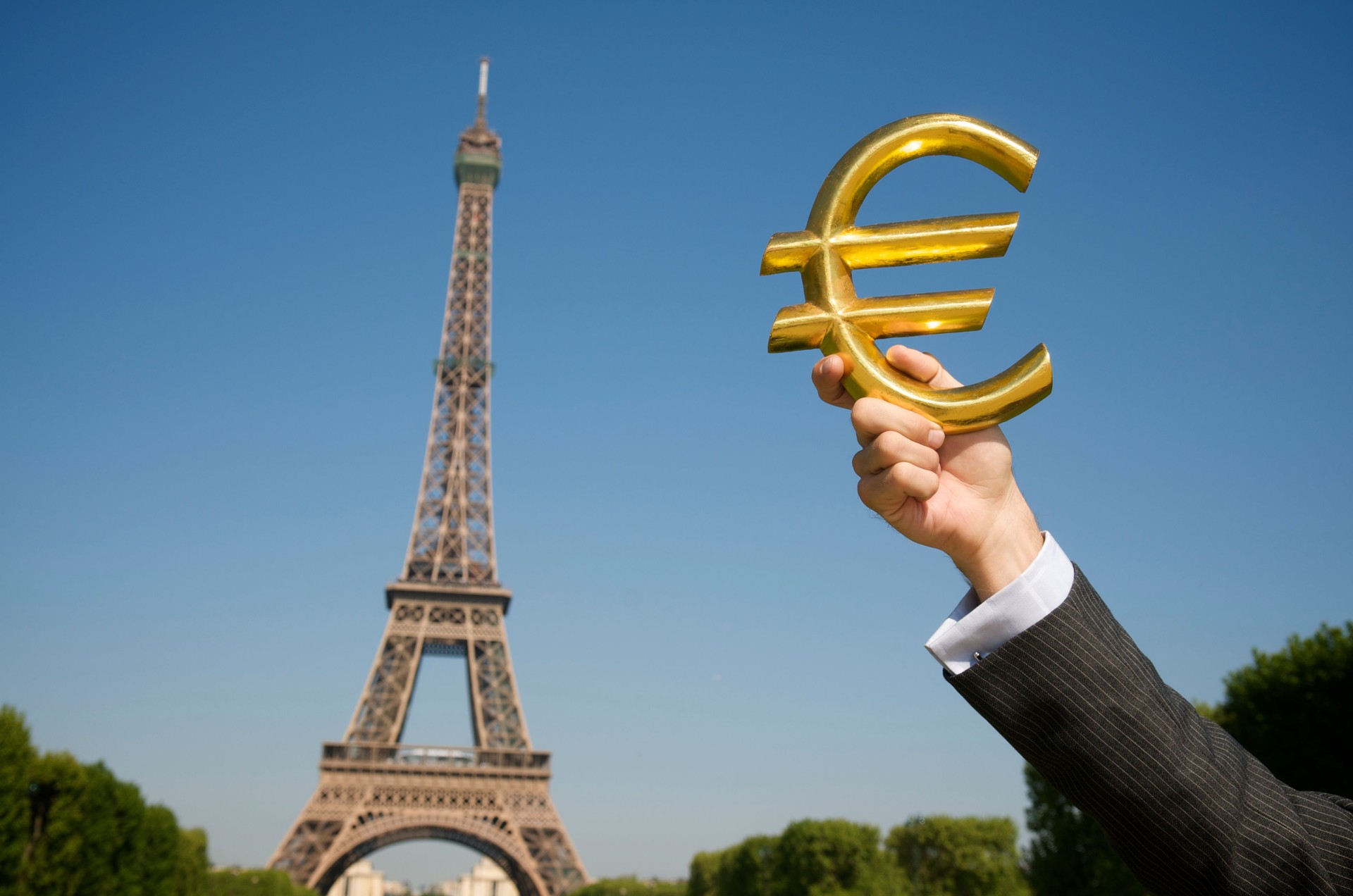 Businessman Holds Gold Euro in Front of Eiffel Tower